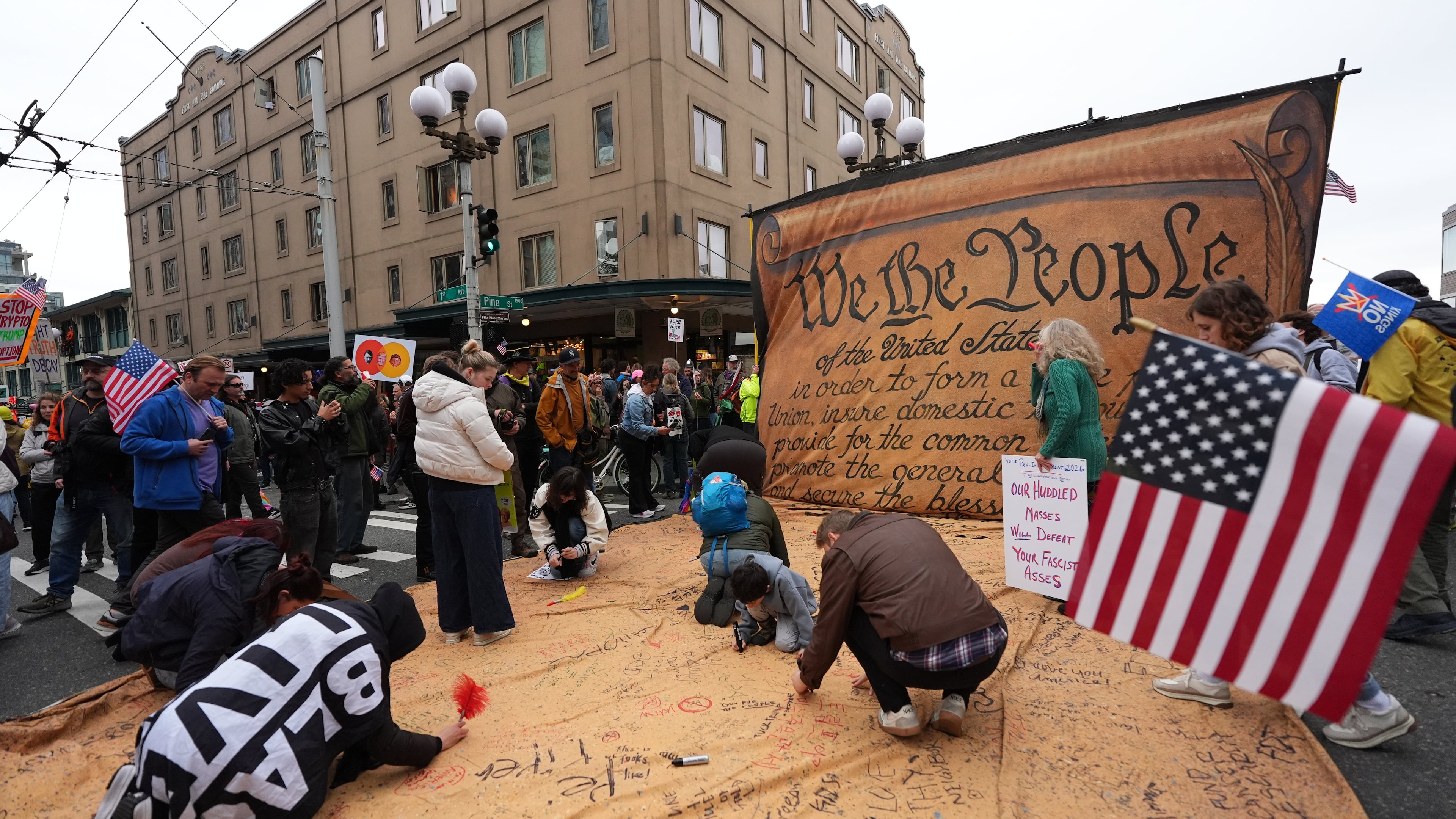 People are signing a giant Constitution as they take part in a "No Kings" protest Saturday, Oct. 18, 2025, in Seattle. (AP Photo/Lindsey Wasson)