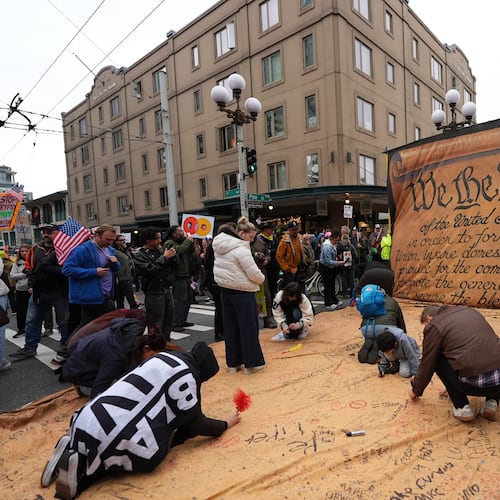 People are signing a giant Constitution as they take part in a "No Kings" protest Saturday, Oct. 18, 2025, in Seattle. (AP Photo/Lindsey Wasson)