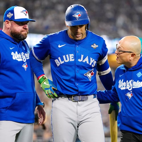 Toronto Blue Jays' George Springer, center, walks off the field as he leaves with an injury with manager John Schneider, left, and first assistant athletic trainer Voon Chong, right, during the seventh inning in Game 3 of baseball's World Series against the Los Angeles Dodgers in Los Angeles, Monday, Oct. 27, 2025. (Frank Gunn/The Canadian Press via AP)