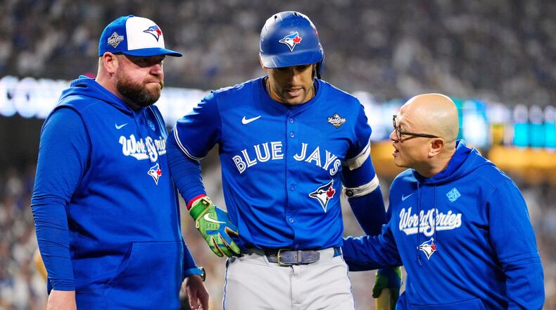 Toronto Blue Jays' George Springer, center, walks off the field as he leaves with an injury with manager John Schneider, left, and first assistant athletic trainer Voon Chong, right, during the seventh inning in Game 3 of baseball's World Series against the Los Angeles Dodgers in Los Angeles, Monday, Oct. 27, 2025. (Frank Gunn/The Canadian Press via AP)
