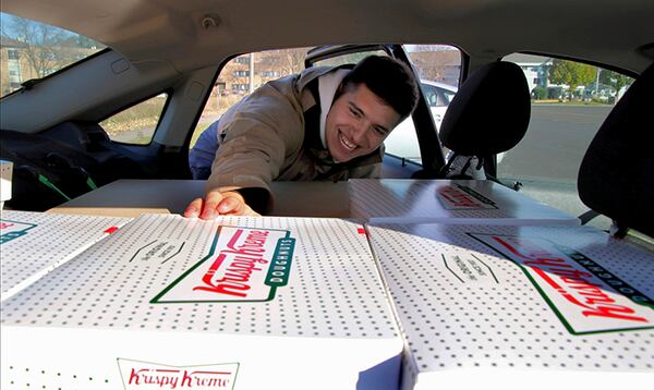 Jayson Gonzalez reaches into his car for another box of Krispy Kreme doughnuts for customers in Little Canada, Minn., who ordered online. Gonzalez, a Minnesota college student, says Krispy Kreme has told him to stop making doughnut runs to Iowa. 