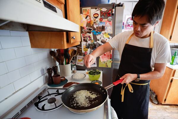 Heat canola oil in a wok or large saute pan over medium-high heat. Add the garlic and ginger and saute, stirring constantly, for about 15 seconds. (Natrice Miller/AJC)