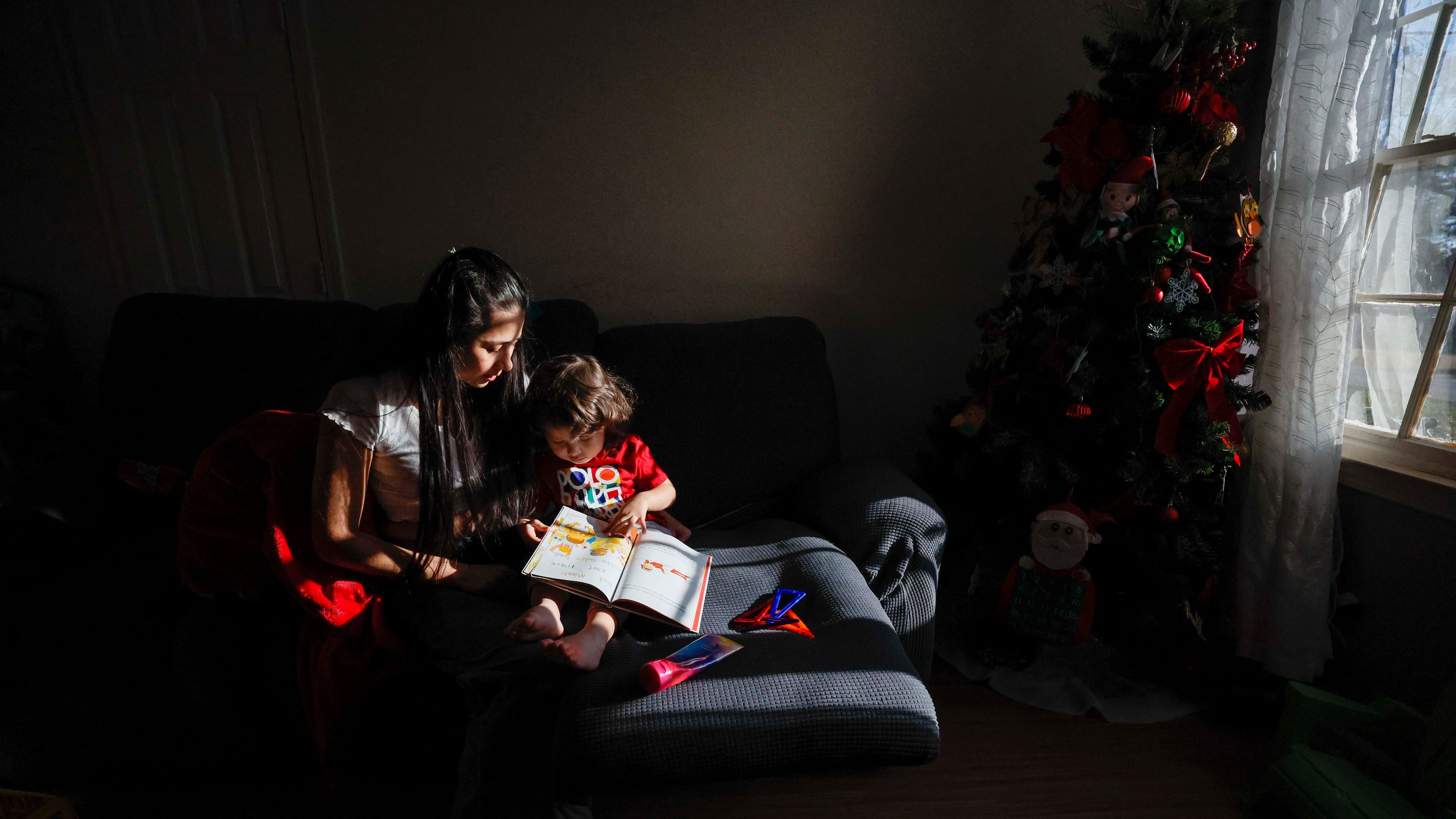 Ceudy Gutierrez reads a book to her 2-year-old son, Matias, at their home in Buford, GA, on Tuesday, Nov. 18, 2025. Ceudy Gutierrez is struggling to make ends meet for herself and her three young kids following her husband’s ICE arrest earlier this fall. (Miguel Martinez/ AJC)