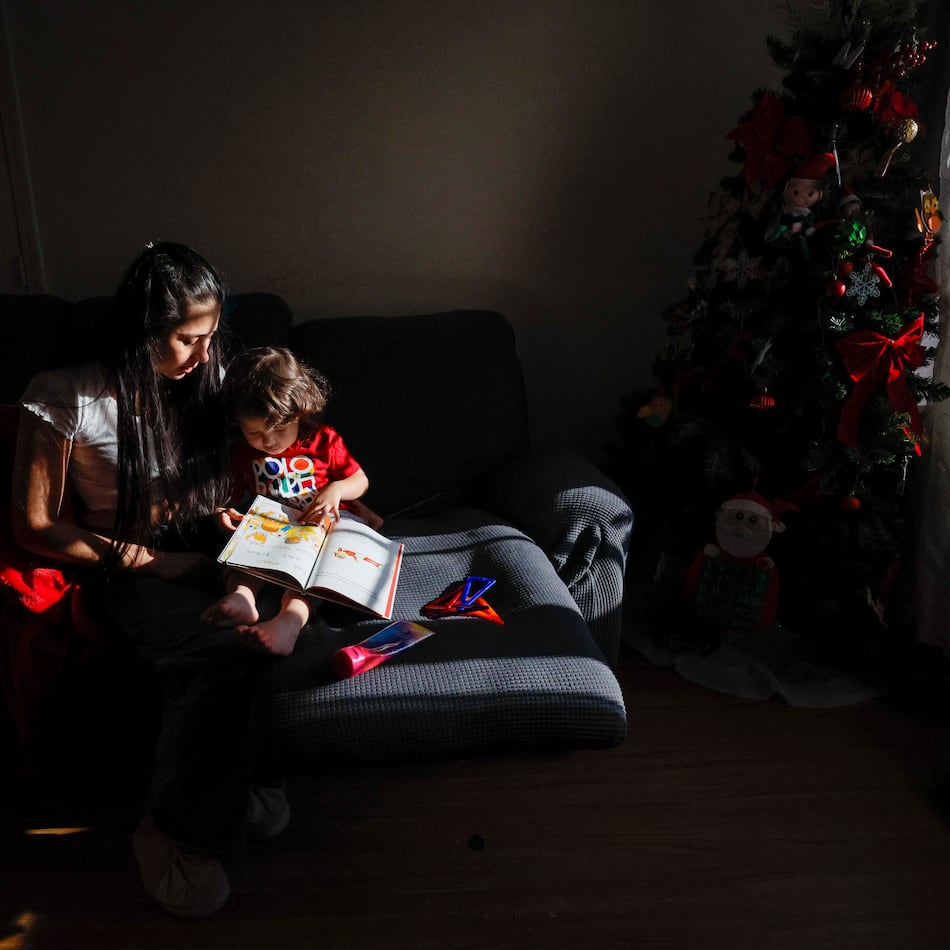 Ceudy Gutierrez reads a book to her 2-year-old son, Matias, at their home in Buford, GA, on Tuesday, Nov. 18, 2025. Ceudy Gutierrez is struggling to make ends meet for herself and her three young kids following her husband’s ICE arrest earlier this fall. (Miguel Martinez/ AJC)