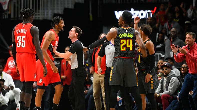 A referee, third from left, keeps Portland Trail Blazers forward Trevor Ariza, second from left, and Atlanta Hawks guard Trae Young (11) separated during a scuffle in the second half of an NBA basketball game Saturday, Feb. 29, 2020, in Atlanta. Ariza was charged with a technical foul. (AP Photo/John Amis)