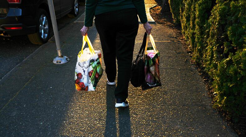 FILE - A woman carries reuable shopping bags to her car March 16, 2026, in Portland, Ore. (AP Photo/Jenny Kane, File)