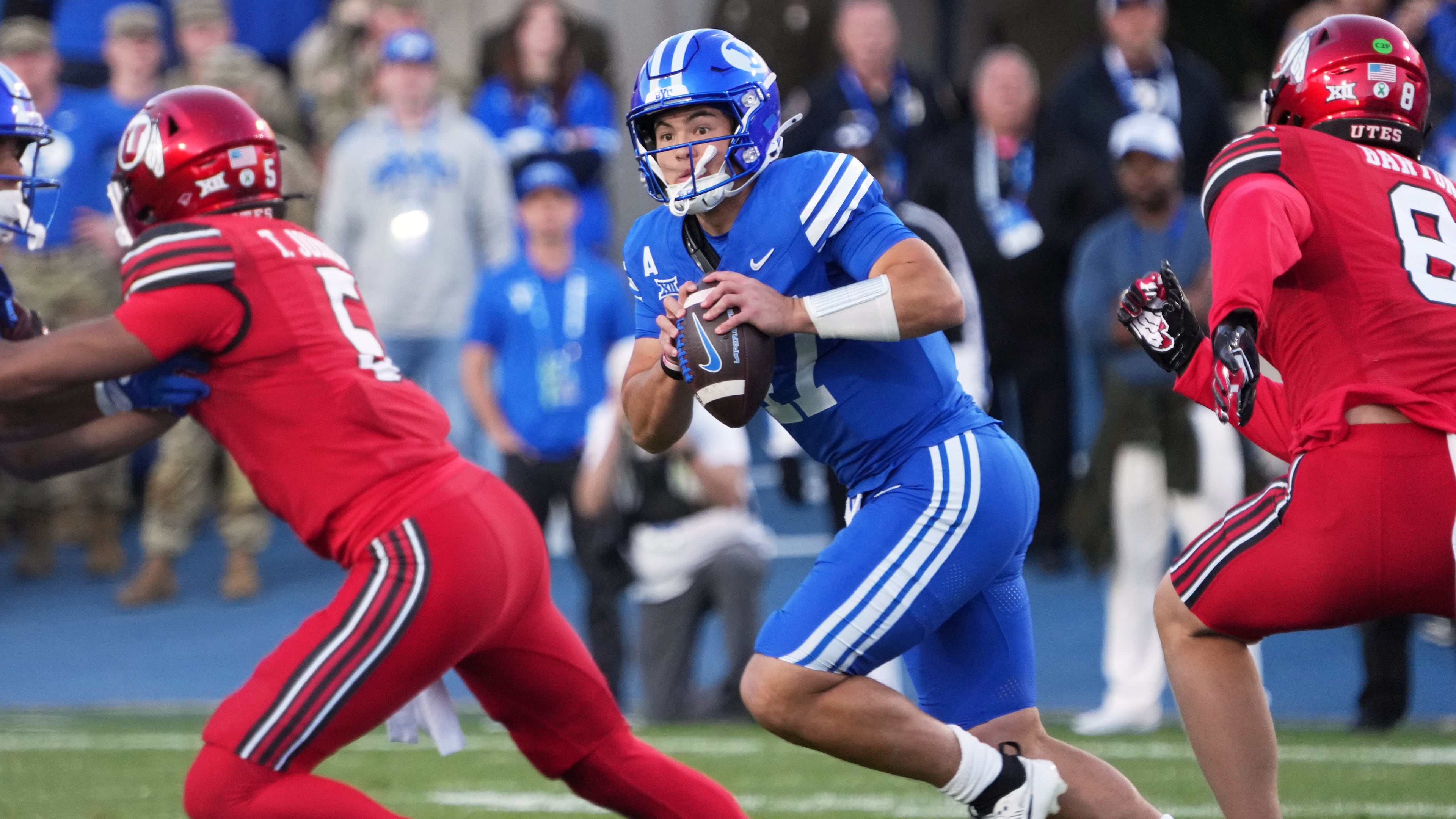 BYU quarterback Bear Bachmeier (47) rolls out to pass as Utah linebacker Lander Barton (8) and Utah safety Tao Johnson (5) defend during the first half of an NCAA college football game Saturday, Oct. 18, 2025, in Provo, Utah. (AP Photo/George Frey)
