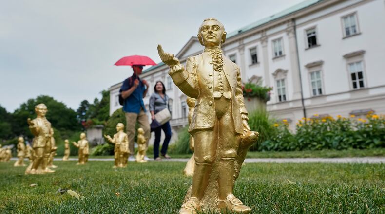 People pass 400 gold colored plastic Mozart sculptures by German artist Ottmar Hoerl from Nuremberg before the 270th birthday of composer Wolfgang Amadeus Mozart in Salzburg, Austria, Wednesday, July 15, 2026. (AP Photo/Matthias Schrader)