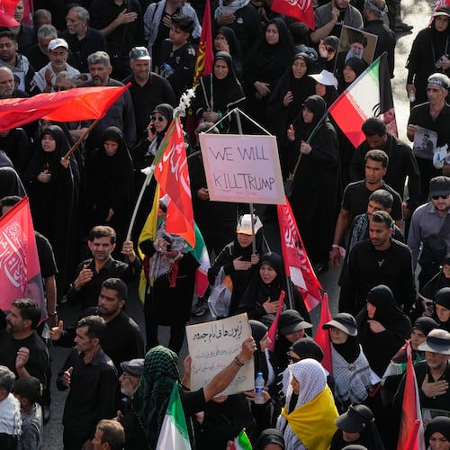 A mourner carries a sign reading "We Will Kill Trump" as people make their way to the funeral procession of the slain Iranian Supreme Leader Ayatollah Ali Khamenei in Tehran, Iran, Monday, July 6, 2026. (AP Photo/Vahid Salemi)