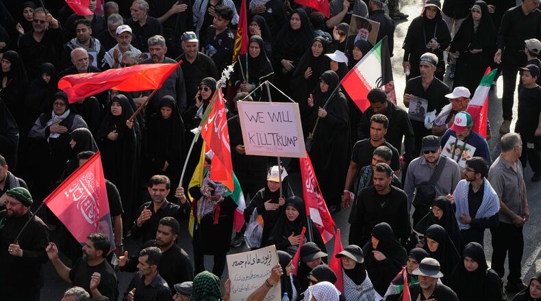 A mourner carries a sign reading "We Will Kill Trump" as people make their way to the funeral procession of the slain Iranian Supreme Leader Ayatollah Ali Khamenei in Tehran, Iran, Monday, July 6, 2026. (AP Photo/Vahid Salemi)