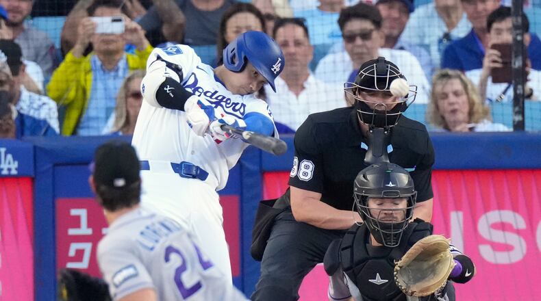 Los Angeles Dodgers' Shohei Ohtani, second from left, hits a solo home run as Colorado Rockies starting pitcher Michael Lorenzen, left, and Braxton Fulford watch during the first inning of a baseball game Tuesday, July 7, 2026, in Los Angeles. (AP Photo/Mark J. Terrill)