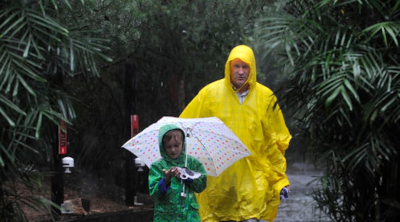 Emma Ferber , 6, and David Ferber, Cumming, walk through the rain at Zoo Atlanta .