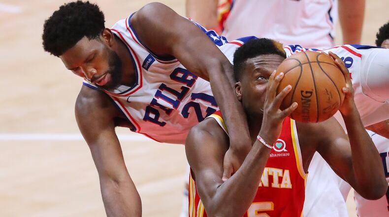 Hawks center Clint Capela gets tangled up with Philadelphia 76ers center Joel Embiid. “Curtis Compton / Curtis.Compton@ajc.com”