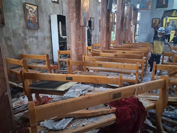 In this photo released by the Syrian official news agency SANA, a Civil Defence worker inspects the damage inside Mar Elias church where a suicide bomber detonated himself in Dweil'a in the outskirts of Damascus, Syria, Sunday June 22, 2025. (SANA via AP)