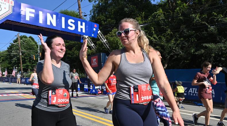 July 4, 2021 Atlanta - Margaret Fordham (left) and Addison Pruitt high-five after crossing the finish line during the second day of 2021 Atlanta Journal-Constitution Peachtree Road Race on Sunday, July 4, 2021. (Hyosub Shin / Hyosub.Shin@ajc.com)