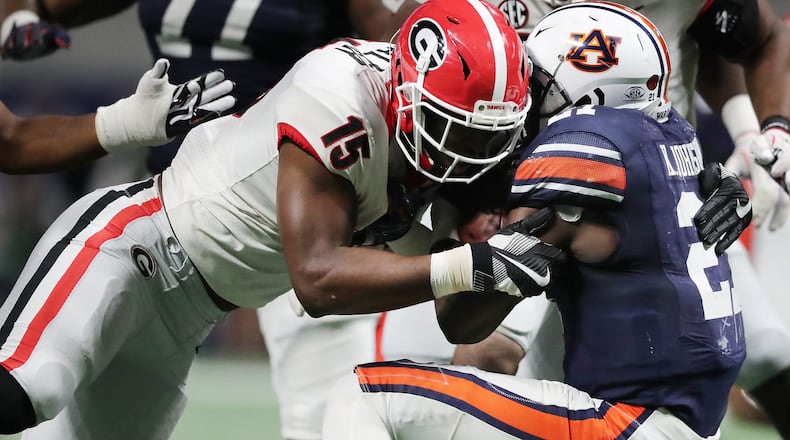 Georgia linebacker D’Andre Walker levels Auburn running back Kerryon Johnson during the SEC Football Championship at Mercedes-Benz Stadium Dec. 2 in Atlanta. UGA stopped tracking concussions by sport once the school had completed a grant application to study the injury. CURTIS COMPTON / CCOMPTON@AJC.COM