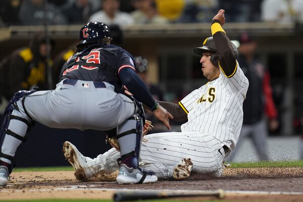 Cleveland Guardians catcher Bo Naylor, left, tags out San Diego Padres' Jose Iglesias on a fielders' choice during the third inning of a baseball game Tuesday, April 1, 2025, in San Diego. San Diego Padres' Fernando Tatis Jr. was safe at first on the play. (AP Photo/Gregory Bull)