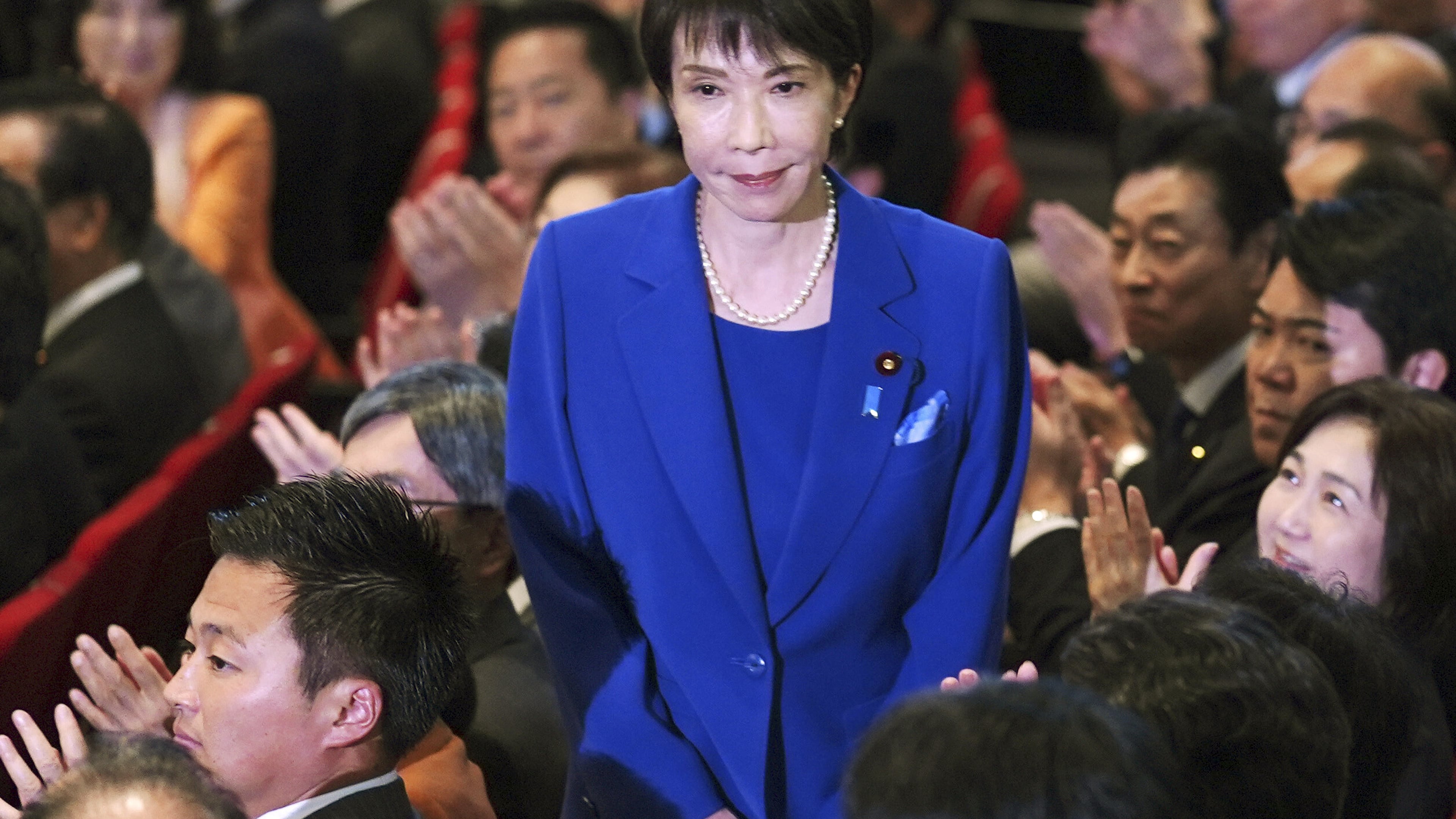 Former Economic Security Minister Sanae Takaichi, center, stands as Takaichi was chosen to a new leader of Japan’s ruling Liberal Democratic Party during the party's leadership election in Tokyo, Japan, Saturday, Oct. 4, 2025. (Yohei Fukai/Kyodo News via AP)