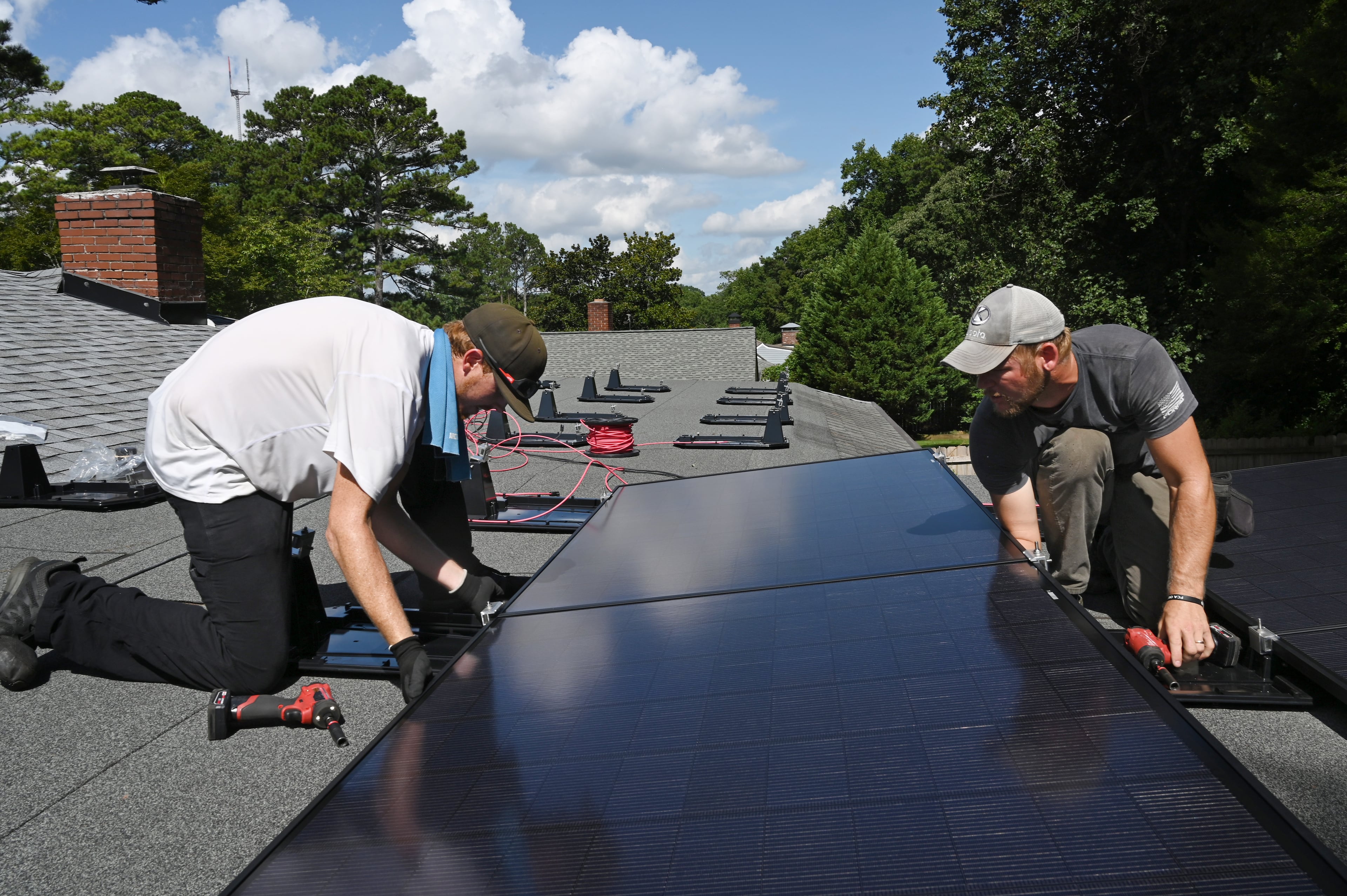 Justin Shelnutt (left) and Ryan Johnson, both with Custom Solar Solutions, install solar panels on the roof of an Atlanta home. (Hyosub Shin/AJC)
