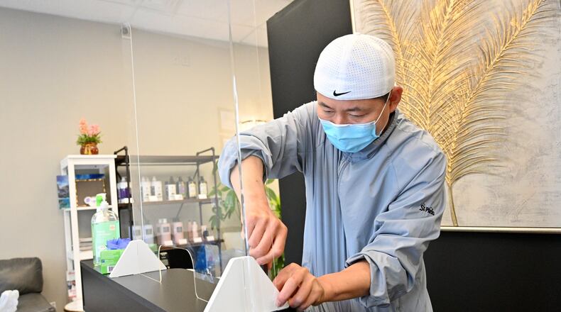 Jay Choi, owner of Kara Hair, installs a plexiglass at front desk as a part of preparations before he opens his hair salon on Thursday, April 23, 2020. “I try everything I can to protect our customers and our staff from Coronavirus. We will operate by appointment only and ask a customer to wear a mask,” said Jay Choi. Gov. Brian Kemp announced a gradual reopening of the economy Monday. Businesses including salons, barbershops, tattoo parlors, gyms, bowling alleys and nail salons will be able to welcome customers Friday. HYOSUB SHIN / HYOSUB.SHIN@AJC.COM