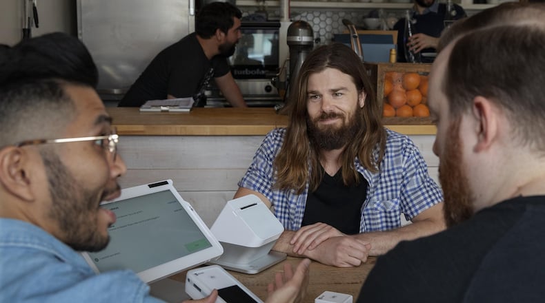 Dan Price, owner of Gravity Payments, center, with a customer and a member of his sales team in Seattle, March 27, 2019. Four years ago, Price raised the minimum wage for all his employees to $70,000 a year. “Gravity shows that at least for some companies in some industries, it is possible to thrive while treating even the lowest-level workers with dignity. And that’s not the death of capitalism but perhaps part of its rebirth,” writes columnist Nicholas Kristof. (Ruth Fremson/The New York Times)