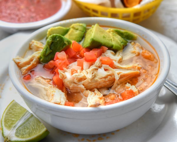 Chicken and Rice Soup (garnished with avocado, chopped tomatoes and onions) from Taxco. (Chris Hunt for The Atlanta Journal-Constitution)