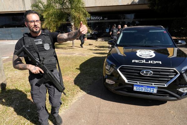 Federal police officers stand at the the Secretariat of Penitentiary Administration office where Brazil's former President Jair Bolsonaro, who is on trial for allegedly attempting to stage a coup, after he arrived to be fitted with an electronic ankle monitor in Brasilia, Brazil, Friday, July 18, 2025. (AP Photo/Eraldo Peres)