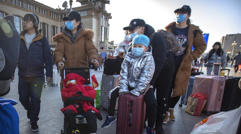Travelers wear face masks as they walk outside of the Beijing Railway Station in Beijing, Monday, Jan. 20, 2020. China reported Monday a sharp rise in the number of people infected with a new coronavirus, including the first cases in the capital. The outbreak coincides with the country’s busiest travel period, as millions board trains and planes for the Lunar New Year holidays. (AP Photo/Mark Schiefelbein)