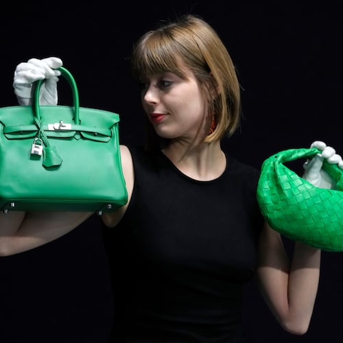 FILE - A Bonhams employee displays a Hermes: a Bambou Swift Leather Birkin 25 bag, left, and a Bottega Veneta: a Parakeet Green Lambskin Mini Jodie, right, at the auction rooms in London on Feb. 26, 2024. (AP Photo/Kirsty Wigglesworth, File)