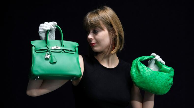 FILE - A Bonhams employee displays a Hermes: a Bambou Swift Leather Birkin 25 bag, left, and a Bottega Veneta: a Parakeet Green Lambskin Mini Jodie, right, at the auction rooms in London on Feb. 26, 2024. (AP Photo/Kirsty Wigglesworth, File)