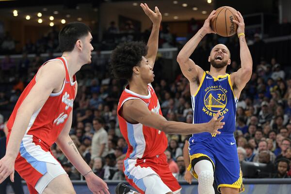 Golden State Warriors guard Stephen Curry (30) handles the ball against Memphis Grizzlies forward Jaylen Wells, center, and center Zach Edey (14) in the first half of an NBA basketball game Tuesday, April 1, 2025, in Memphis, Tenn. (AP Photo/Brandon Dill)