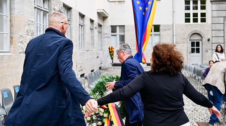 Tobias Korenke, center, grandnephew of Dietrich and Klaus Bonhoeffer and grandson of Ruediger Schleicher, try to remove a wreath of Germany's far right AFD party during a memorial event held by the federal government in the courtyard of the Bendlerblock of the Defence Ministry in occasion of the National Day of Remembrance for Resistance Against Nazi regime in Berlin, Monday, July 20, 2026. (Sebastian Christoph Gollnow/dpa via AP)