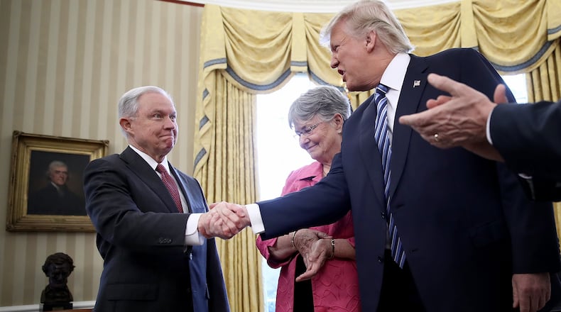 U.S. President Donald Trump (2nd R) shakes the hand of Jeff Sessions after Sessions was sworn in as the new U.S. Attorney General by U.S. Vice President Mike Pence (R) in the Oval Office of the White House February 9, 2017 in Washington, DC. Trump also signed three executive orders immediately after the swearing in ceremony. Also pictured is Sessions's wife, Mary (2nd L), holding the bible. (Photo by Win McNamee/Getty Images)