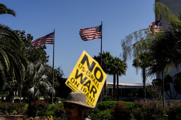 An anti-war demonstrator holds a sign outside the Wilshire Federal Building in Los Angeles Sunday, June 22, 2025, following U.S. airstrikes on Iran's nuclear facilities. (AP Photo/Jae C. Hong)