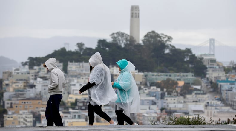 Visitors take in city views at Hyde and Lombard streets as rain begins to soak the Bay Area, in San Francisco, Sunday, Feb. 15, 2026. (Brontë Wittpenn/San Francisco Chronicle via AP)