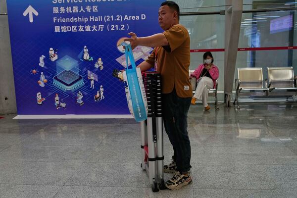 A man reacts near a board showing robots at the 137th Canton Fair in Guangzhou in southern China's Guangdong province on Wednesday, April 16, 2025. (AP Photo/Ng Han Guan)