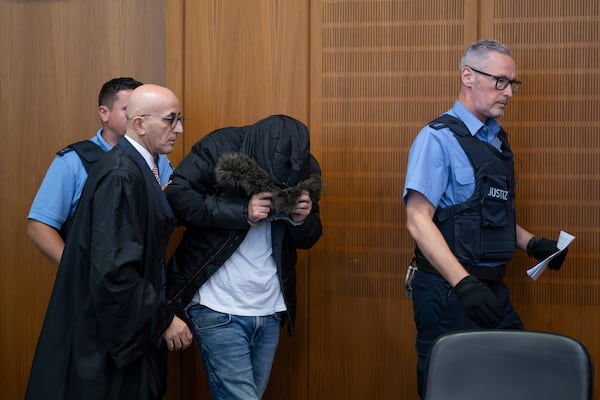 A Syrian doctor, center, accused of torture and war crimes in his Syrian homeland, is led into the courtroom next to his lawyer Oussama Al-Agi, 2nd left, for the verdict, in the Higher Regional Court in Frankfurt, Germany, Monday, June 16, 2025. (Boris Roessler/dpa via AP)