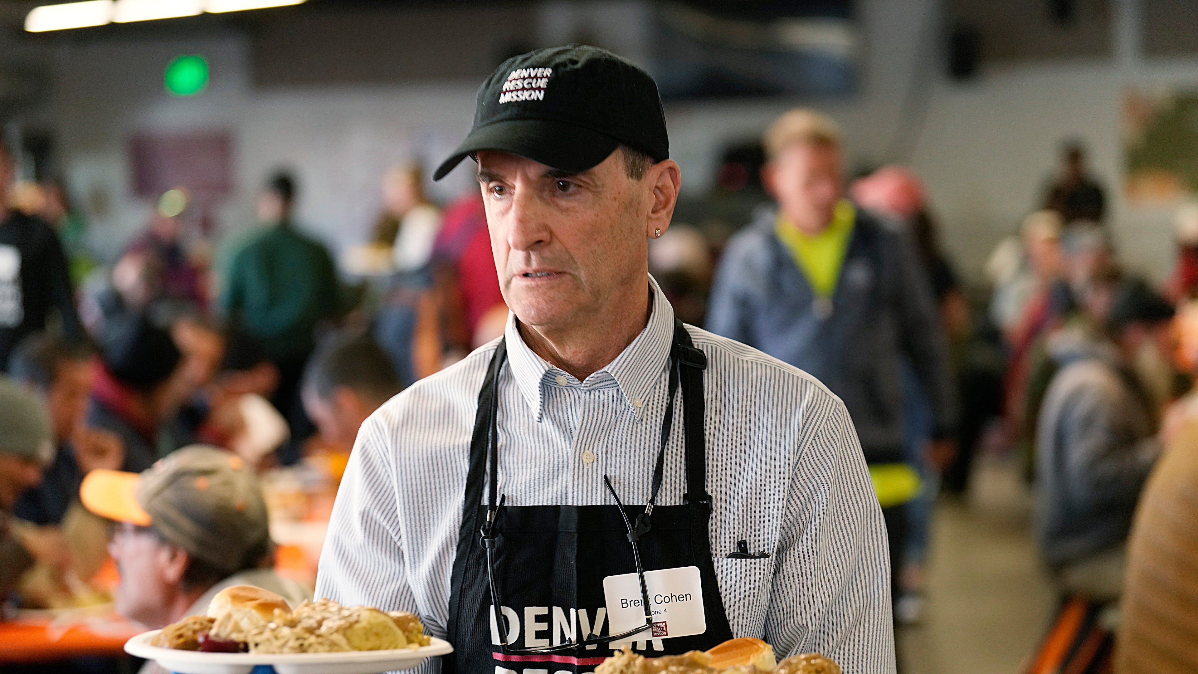 FILE - Volunteer Brent Cohen carries plates of food to guests during the annual Thanksgiving banquet at the Denver Rescue Mission on Nov. 22, 2023, in Denver. (AP Photo/David Zalubowski, File)