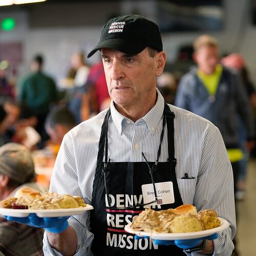 FILE - Volunteer Brent Cohen carries plates of food to guests during the annual Thanksgiving banquet at the Denver Rescue Mission on Nov. 22, 2023, in Denver. (AP Photo/David Zalubowski, File)