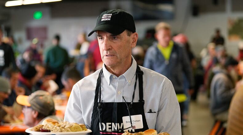 FILE - Volunteer Brent Cohen carries plates of food to guests during the annual Thanksgiving banquet at the Denver Rescue Mission on Nov. 22, 2023, in Denver. (AP Photo/David Zalubowski, File)