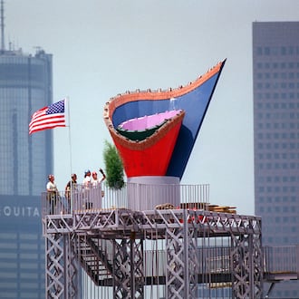 With a flag completing the picture, ironworkers admire their efforts after installing the Olympic Cauldron atop its 116-foot-high tower on May 30, 1996. The Cauldron, made of stainless steel, has a terra cotta rim of Georgia red clay. (Joey Ivansco/AJC 1996)