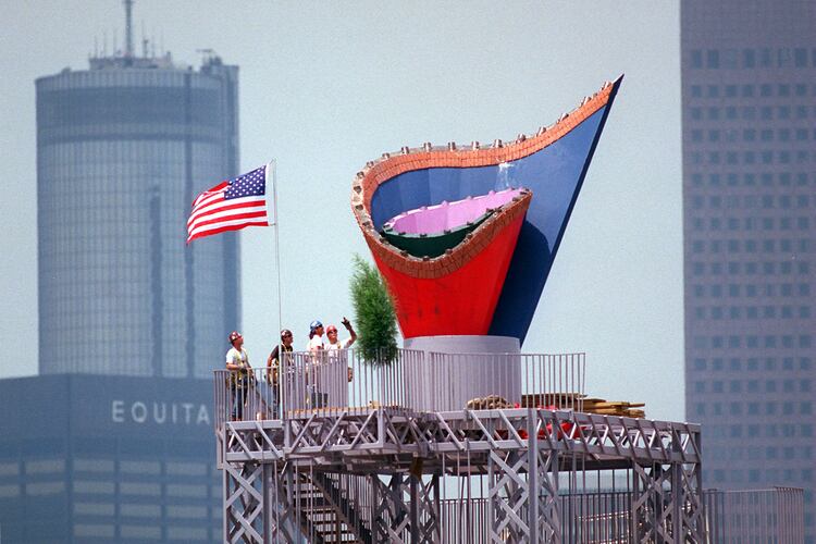 With a flag completing the picture, ironworkers admire their efforts after installing the Olympic Cauldron atop its 116-foot-high tower on May 30, 1996. The Cauldron, made of stainless steel, has a terra cotta rim of Georgia red clay. (Joey Ivansco/AJC 1996)
