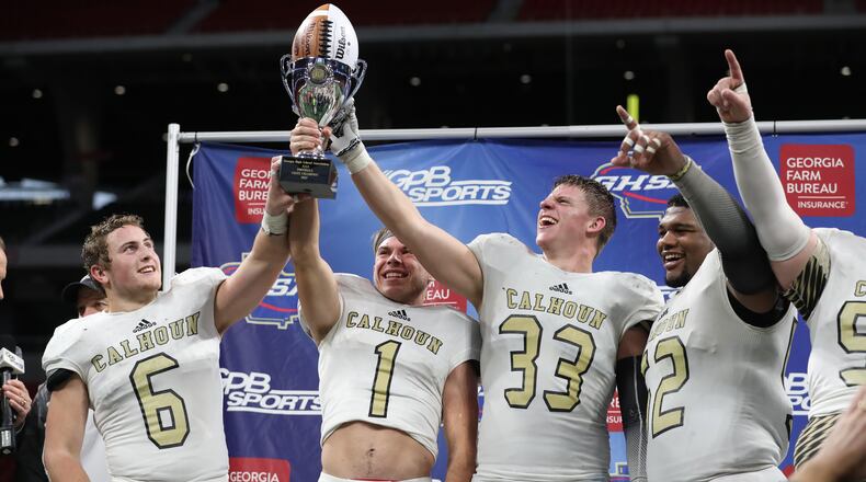 Calhoun's Bailey Lester (6), Porter Law (1), Zeke Nance (33) and C.J. Fuller (52) celebrate with the trophy after their win against Peach County during the Class AAA Championship at Mercedes-Benz Stadium Friday, December 8, 2017, in Atlanta. Calhoun won 10-6. PHOTO / JASON GETZ