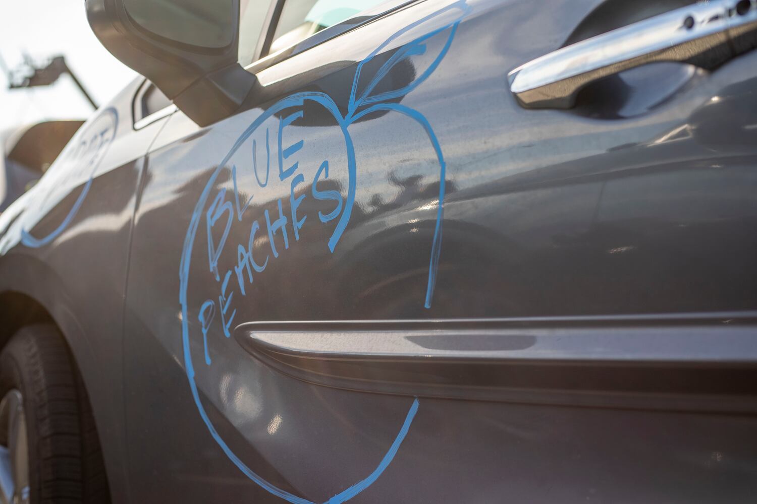 01/04/2021 — Atlanta, Georgia — A drawing of a blue peach, to symbolize the Georgia Democratic Party, is displayed on a car during a Georgia Democrat U.S. Senate campaign rally in Atlanta’s Peoplestown neighborhood, Monday, January 4, 2021. (Alyssa Pointer / Alyssa.Pointer@ajc.com)