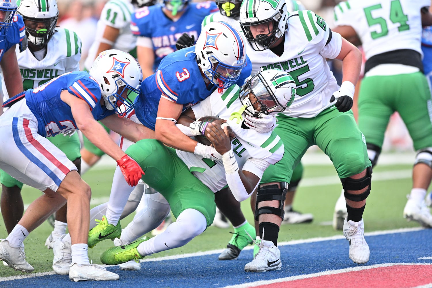 Walton middle linebacker Noah Lavallee (3) and free safety Tate Adams (20) are unable too top Roswell quarterback Trey Smith (1) from scoring early in the half of a game Friday, August 29, 2025 at Walton High School. (Daniel Varnado/For the Atlanta Journal-Constitution)