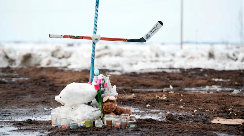 A memorial, including a cross made out of hockey sticks, sits near the intersection of a fatal bus crash near Tisdale, Saskatchewan, Canada, Monday, April, 9, 2018. A bus carrying the Humboldt Broncos junior hockey team crashed last Friday night, April 6,  into a truck, killing 15 and sending over a dozen more to the hospital. (Jonathan Hayward/The Canadian Press via AP)