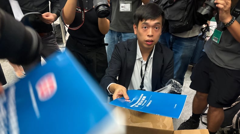 A man gives out copies of public consultation documents for Hong Kong's first five-year plan to reporters at the government headquarters in Admiralty district of Hong Kong, Monday, June 15, 2026. (AP Photo/Kanis Leung)