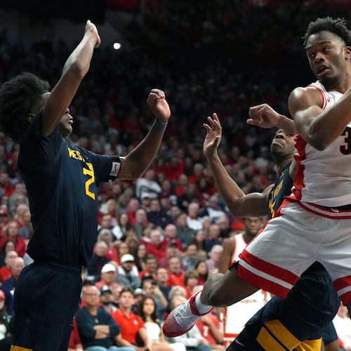 Arizona forward Tobe Awaka drives on West Virginia guard Amir Jenkins (2) and guard Honor Huff during the second half of an NCAA college basketball game, Saturday, Jan. 24, 2026, in Tucson, Ariz. (AP Photo/Rick Scuteri)