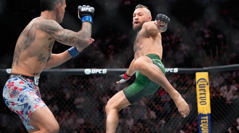 Conor McGregor, right, jumps into the air for a kick as he fights Max Holloway in a welterweight fight at the UFC 329 mixed martial arts event Saturday, July 11, 2026, in Las Vegas. (AP Photo/John Locher)