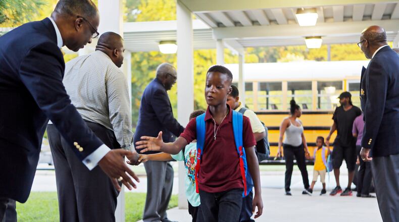 Members of the 100 Black Men of Atlanta greet students as they arrive for the first day of school at Hamilton E. Holmes Elementary in East Point on Aug. 6. BOB ANDRES /BANDRES@AJC.COM